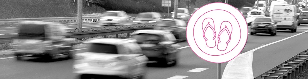 Autofahren mit Flip-Flops oder barfuß – erlaubt oder verboten? Ansicht einer Autobahn mit fahrenden Autos und einem Straßenschild, das Flip-Flops zeigt – symbolisch für die Frage, ob Autofahren mit Badeschlappen erlaubt ist.