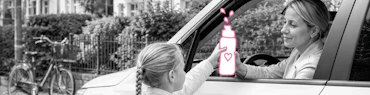 Eine Mutter sitzt im Auto verabschiedet sich von ihrem Kind, was zur Schule geht